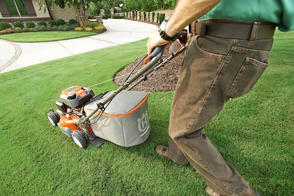 Gardener mowing a striped lawn